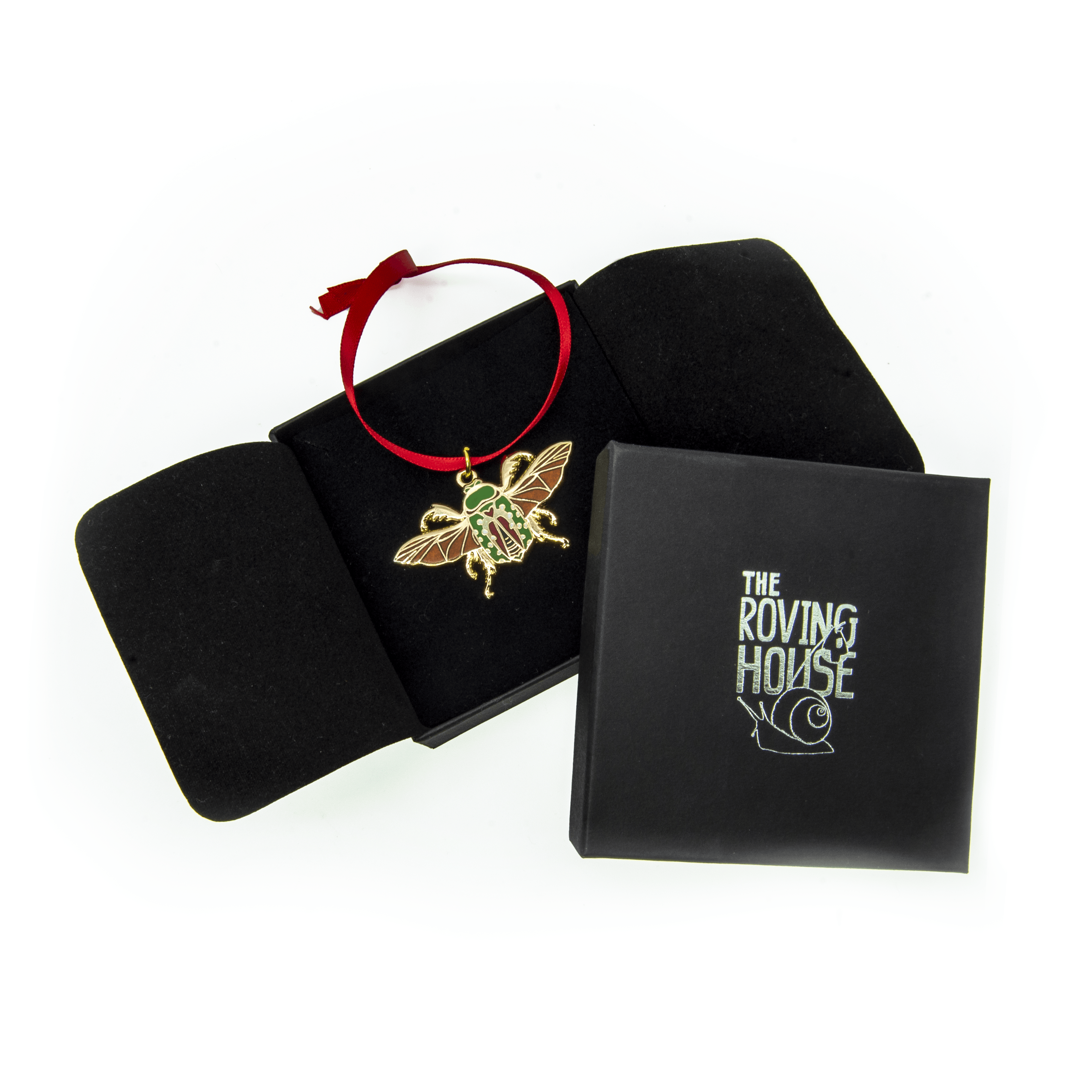 picture of a mistletoe beetle in a "pinned specimen" position in gold metal with green and red shell and orange wings pictured in its box, the cover shows the roving house "Rover" snail with bindle logo.